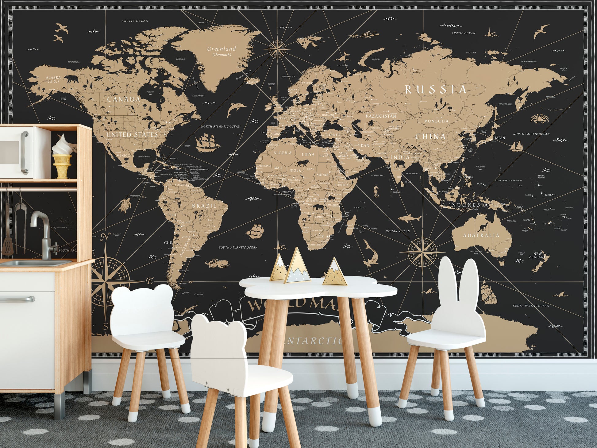Vintage Black Golden World Map wallpaper mural behind white bear and bunny chairs and a play table in a kids room