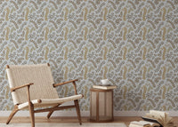 Vintage Foliage Golden and Gray wallpaper behind a woven rattan armchair and caned side table