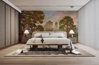 Watercolor Lake Sunset Forest wallpaper mural behind a white bed with rattan wardrobes in a bedroom