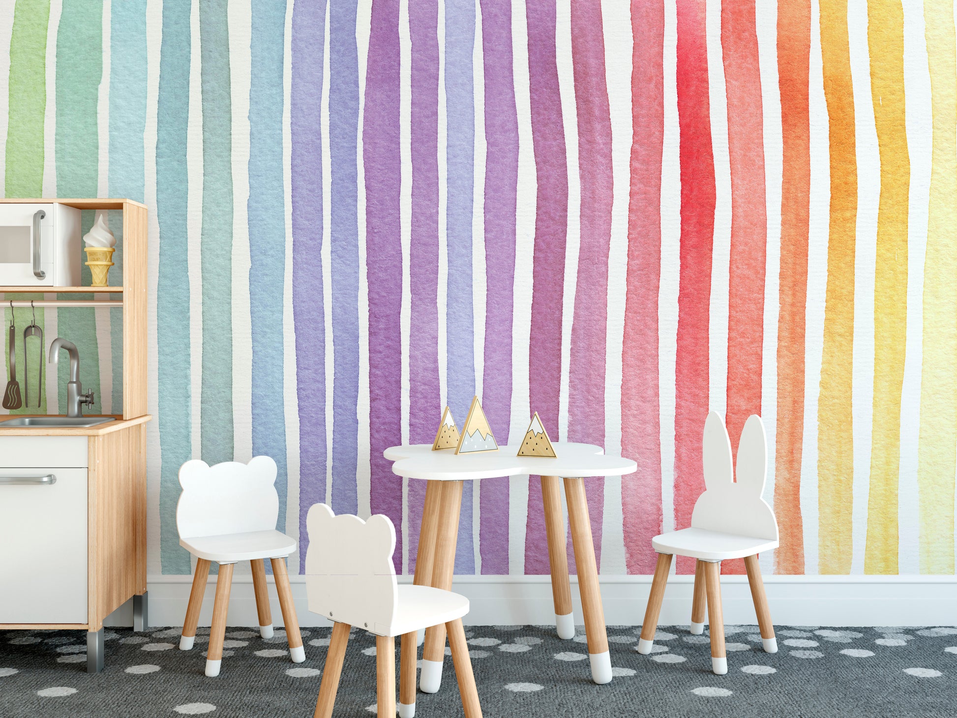 Watercolor Rainbow Striped wallpaper mural with vivid rainbow stripes beside a wooden climbing frame and chalkboard in a playroom