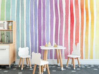 Watercolor Rainbow Striped wallpaper mural with vivid rainbow stripes beside a wooden climbing frame and chalkboard in a playroom