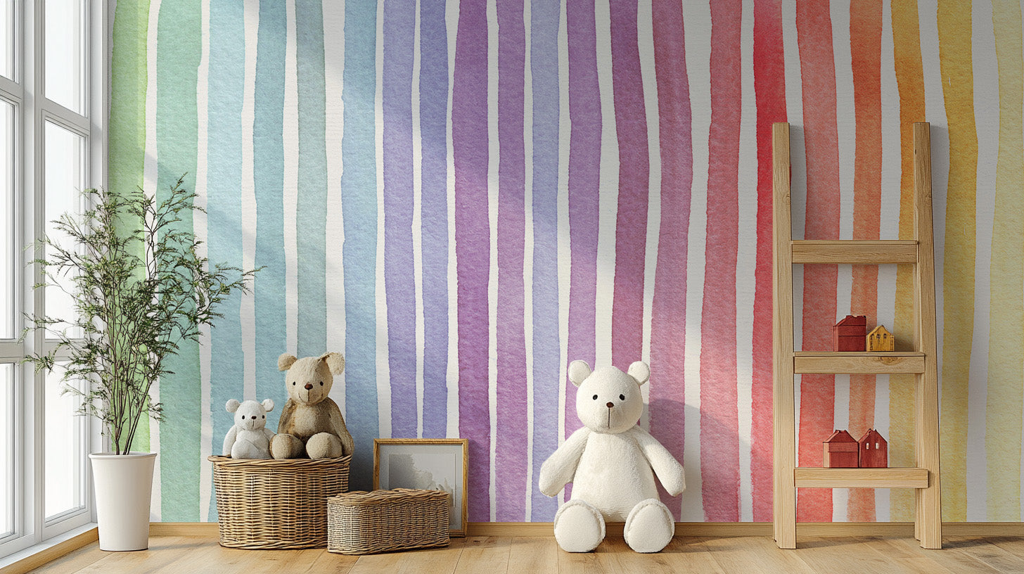 Watercolor Rainbow Striped wallpaper mural in pastel rainbow stripes behind teddy bears and a wooden ladder shelf in a kids room