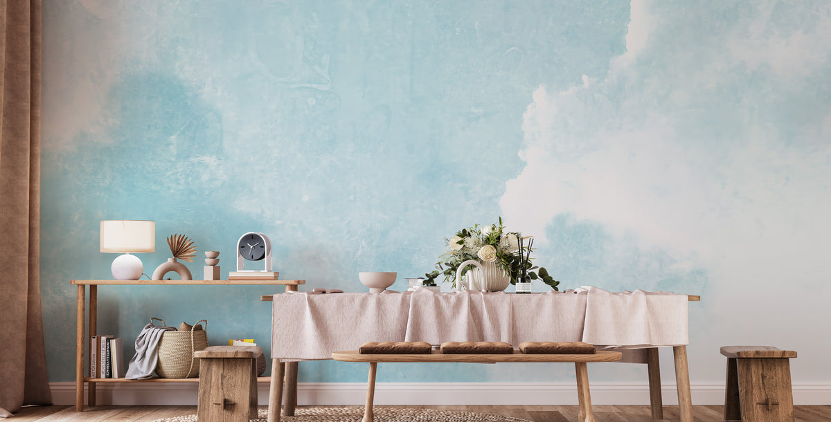 Watercolor Sky Clouds wallpaper mural in soft blue behind a long wood dining table in a dining room