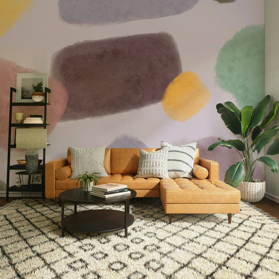 Whimsical Color Blend wallpaper mural of pastel watercolor blobs behind a caramel leather sofa in a living room