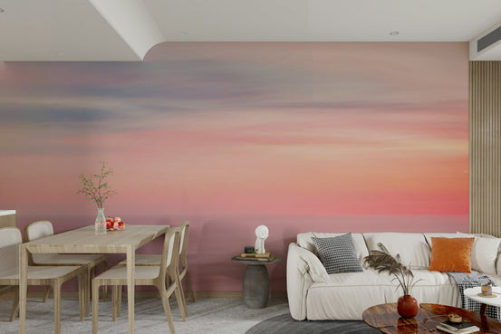 Whispers of Sunset wallpaper mural in pink, purple and orange sky across an open living and dining room with a cream sofa