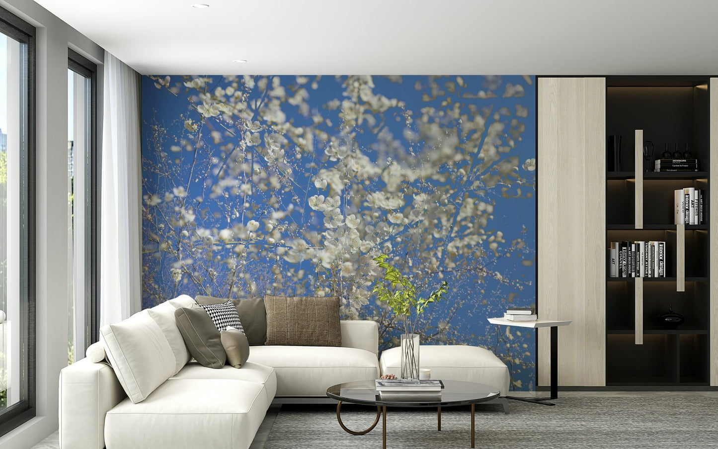 White Blossoms Against a Clear Blue Sky spring photography wall mural behind a white sectional in a modern living room with dark shelving