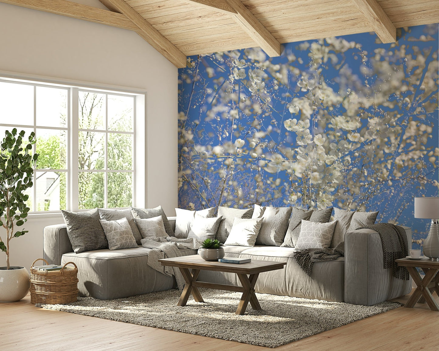 White Blossoms Against a Clear Blue Sky spring photography wall mural under a beamed ceiling behind a gray sectional in a living room
