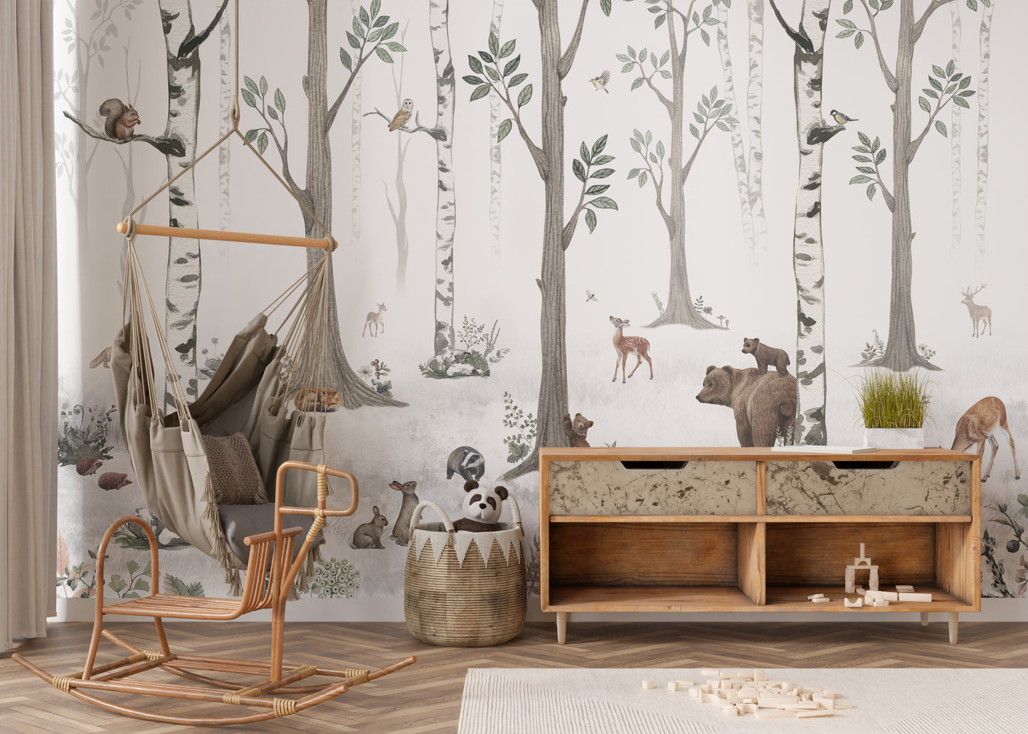 White Forest wallpaper of birch trees and woodland animals behind a rattan hammock chair in a nursery