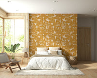 Western-themed wallpaper mural with bronco riders, boots, lassos, and desert icons on a warm ochre background.
