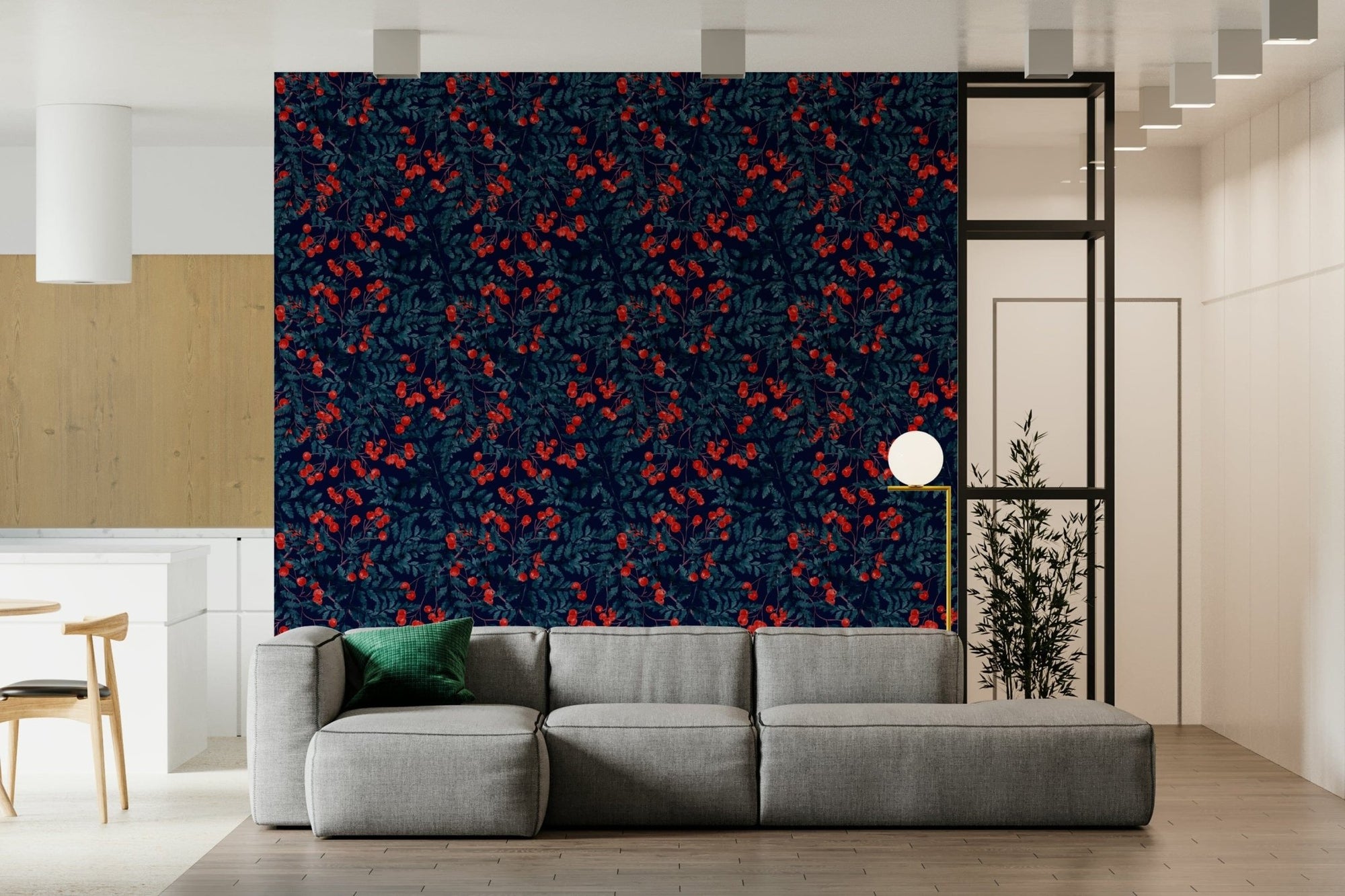 Winter Berries wallpaper with red berries on navy foliage behind a grey sectional sofa in a living room