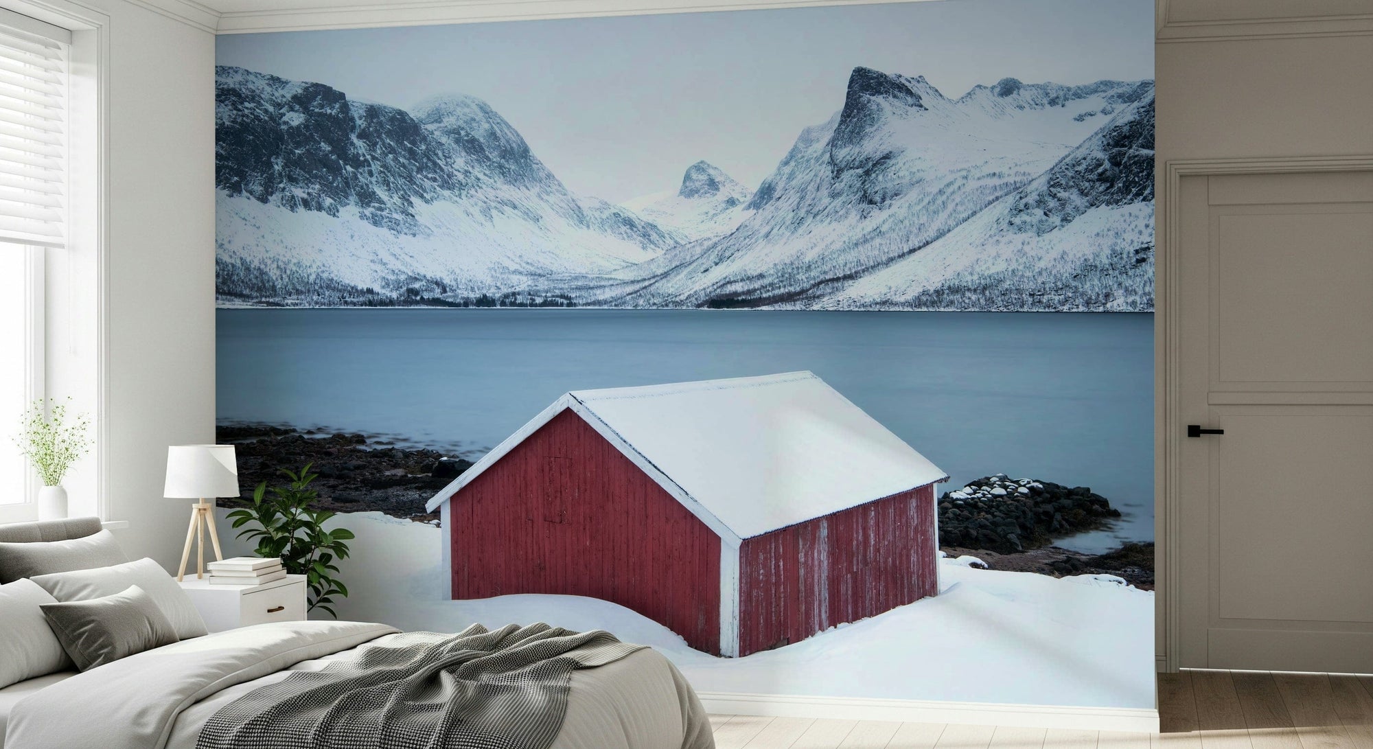 Winter Solitude wallpaper mural of a red cabin by a snowy fjord and mountains behind a bed in a bedroom