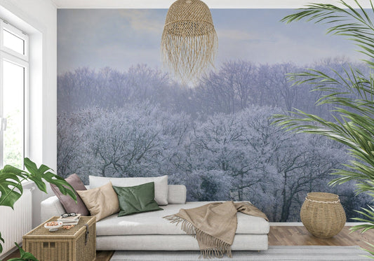 Winter's Whispers wallpaper mural of frost-laden trees behind a white chaise daybed with green cushions in a living room