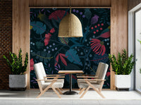 Wonderforest wallpaper mural in navy and pink behind two cream armchairs in a cafe seating area
