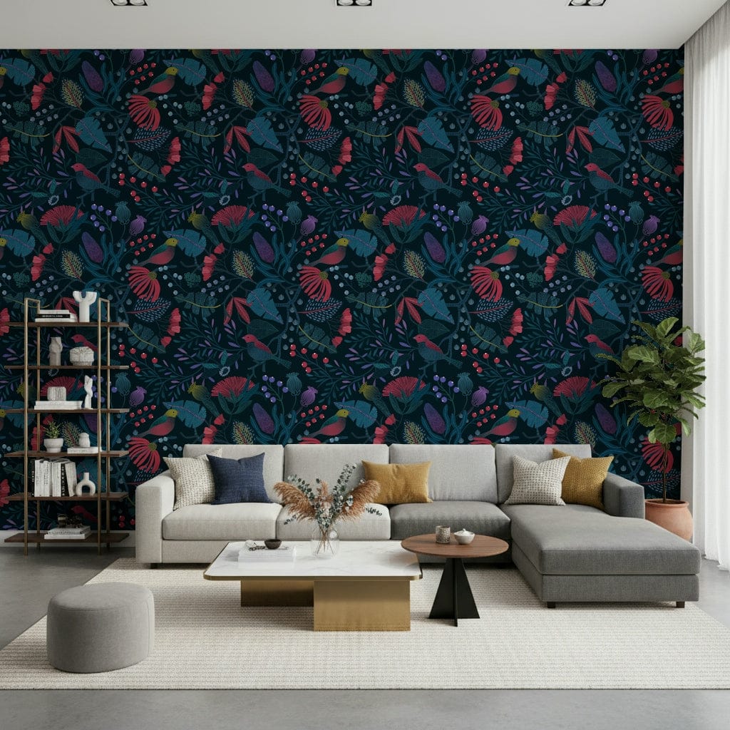 Wonderforest wallpaper with dark navy florals and birds behind a grey sectional sofa and bookshelf in a living room