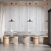 Wood Texture wallpaper in whitewashed planks behind round white tables and rattan stools in a cafe