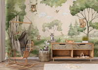 Woodland Joy Kids wallpaper mural with forest animals above a rattan swing chair and wood toy sideboard