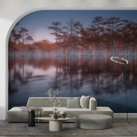 Calm waters reflecting tall trees in Woodland Twilight Lagoon wallpaper print.