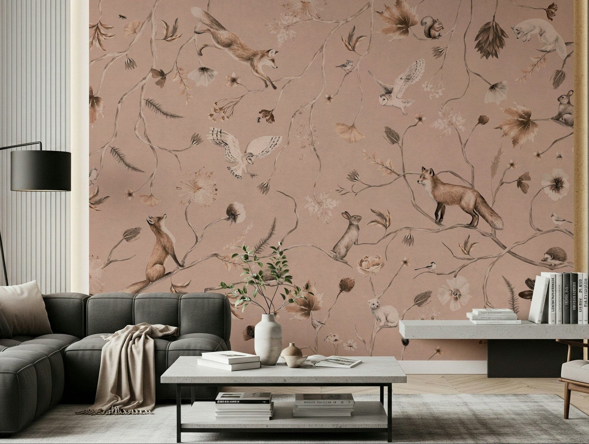 Woodland Whisper wall mural with blush-pink foxes, owls and rabbits behind a dark grey sofa in a living room