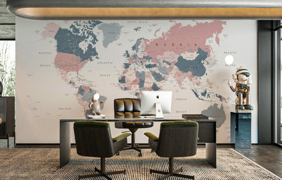 World Map Blush Pink and Indigo wallpaper mural behind a dark executive desk in a home office with armchairs