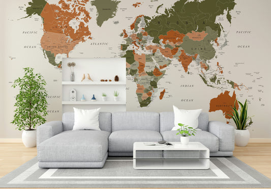 World Map Olive Green wallpaper mural in olive and terracotta behind a grey sectional sofa and white floating shelves in a living room