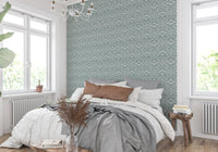 Zenith Leaves wallpaper in sage green behind a white bed with rust and gray linens in a sunny bedroom